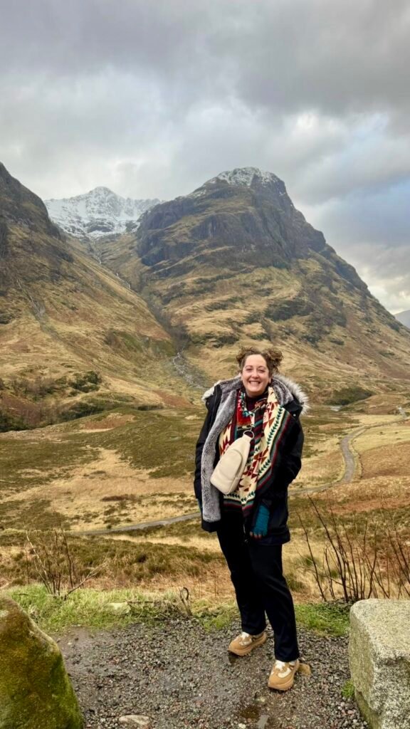 Person standing near mountainous landscape.