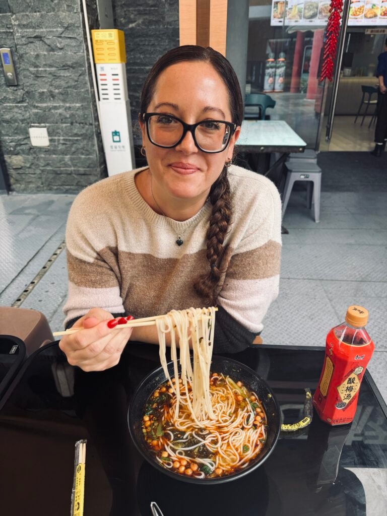 Enjoying handmade Chinese noodles with chopsticks at a local restaurant.