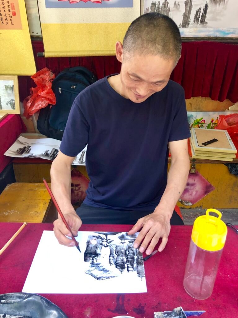 Local artist demonstrating traditional Chinese brush painting in Zhangjiajie